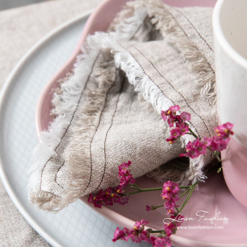 Light grey linen napkin with loose fringes, washed