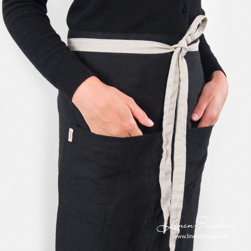 Long black apron with front pockets and waist tie close up view